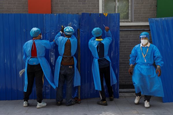 Работници, облечени в предпазни дехи, инсталират барикади около жилищен район за блокиране на епидемията от коронавирус (COVID-19) в Пекин
