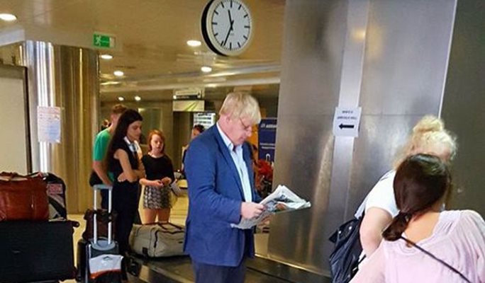 Борис Джонсън чете вестник на летището в Солун при пристигането си в Гърция.
