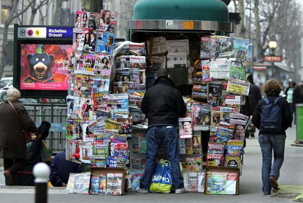 Мъж си купува вестник от будка в Париж.