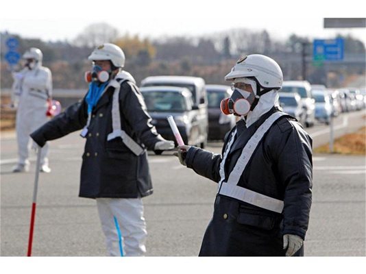 Японски полицаи с противогази са отцепили района на атомната централа и евакуират местните жители.
