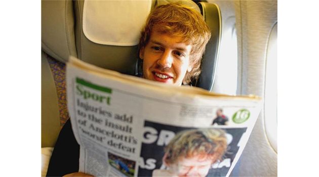 ОБРАТНО: Себастиян Фетел чете вестник, докато лети обратно до пистата "Яс Марина" за първите тестове на новия доставчик на гумите "Пирели".