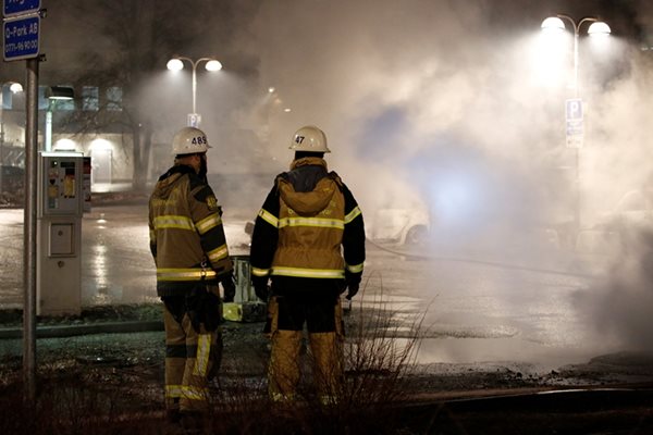 Пожарникари гледат подпалени коли по време на бунта в Стокхолм.