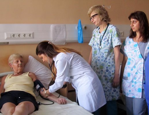 Шефът на Първо вътрешно отделение д-р Кина Никова и д-р Найме Сирачка (която измерва кръвното) следят състоянието на британка, която се лекува в търновската болница.