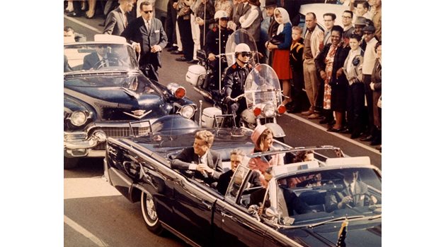 Джон Ф. Кенеди се движи с открита лимузина в Далас мигове преди да бъда разстрелян.