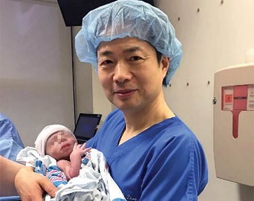 Джон Чжанг държи бебето.