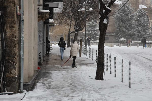 Жена почиства тротоара от снега в София