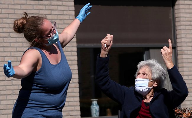 Медицинска сестра пее, за да даде кураж на възрастни хора от старчески дом в Белгия по време на епидемията.
