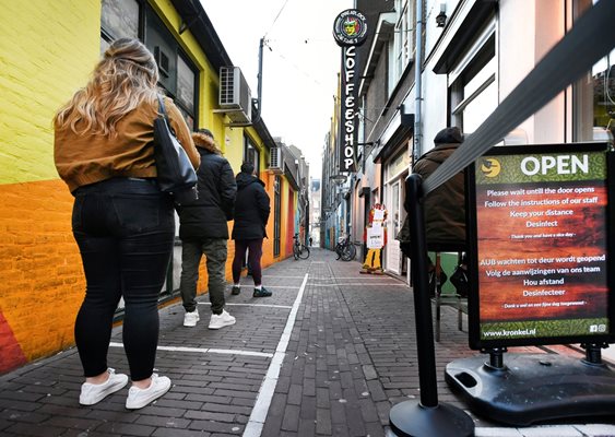 Хора спазват дистанция докато чакат на опашка пред магазин за канабис в Нидерландия.
