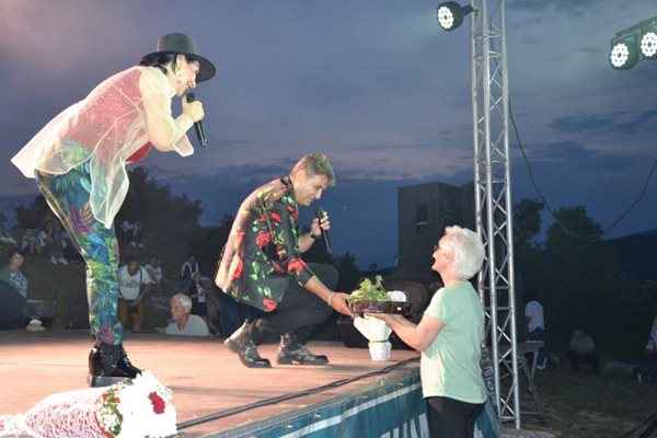 Възрастна момчилградчанка дари тракийска баница на Катя и Здравко от дует "Ритон" докато пееха на сцената край светилището на Орфей в момчилградското село Татул. СНИМКА: НЕНКО СТАНЕВ