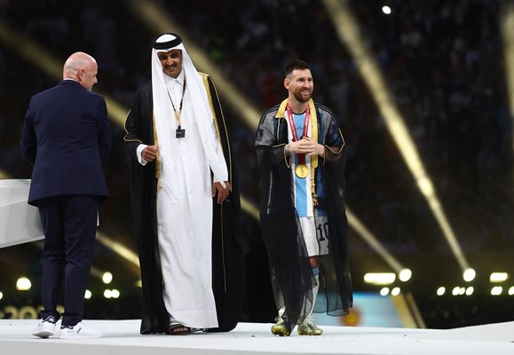 Емирът на Катар Тамим ибн Хамад Ал-Тани току-що е връчил на Лео Меси официален бищ, поръбен със златни нишки. Вляво е президентът на ФИФА Джани Инфантино.