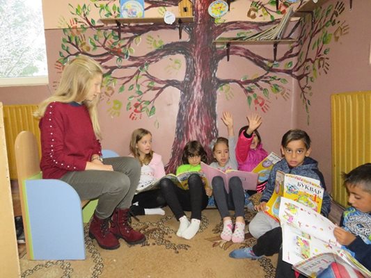 Първолаците и тяхната възпитателка Симона Николова под дървото на четенето в класната стая.
