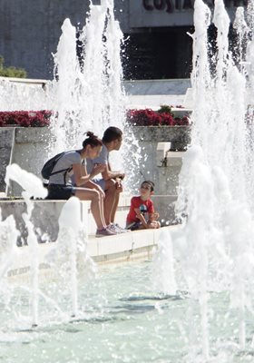 Семейство се наслаждава на хубавото време между фонтаните пред НДК.