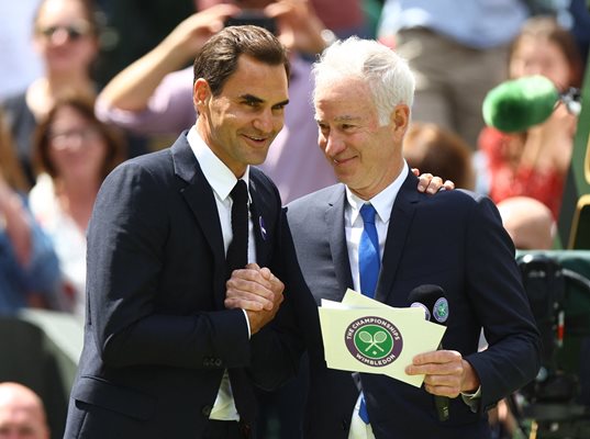 Осемкратният шампион на “Уимбълдън” Роджър Федерер се поздравява с водещия Джон Макенроу (с 3 титли) по време на честването на 100-годишнината на централния корт в Лондон. Снимка: Ройтерс