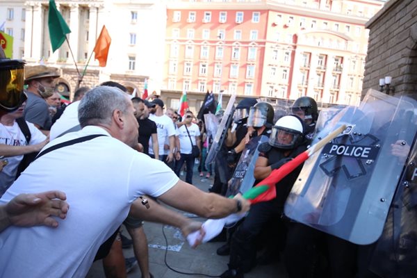 Протестиращ използва българското знаме да налага полицаите.