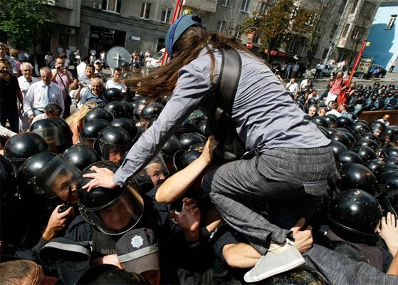 Привърженичка на опозицията се катери по главите на полицаи при протест в Киев.
