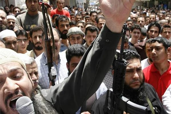 Шейх Абу Шариф с микрофон в ръка говори пред екзалтирана тълпа привърженици.