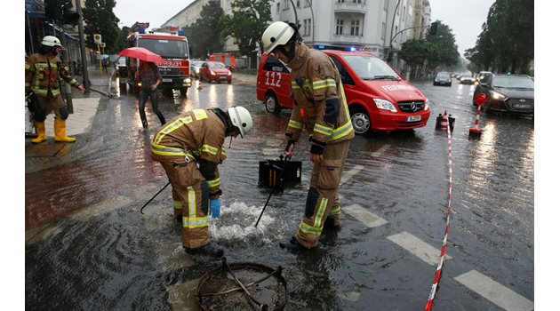 Пожарникари отпушват шахта на наводнена улица в Берлин.