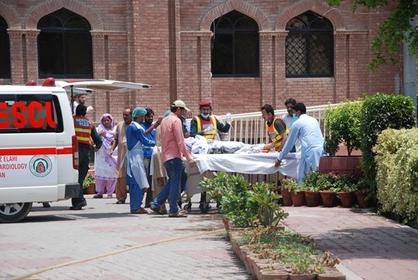 Медицински работници носят тялото на първата жертва на взрива.