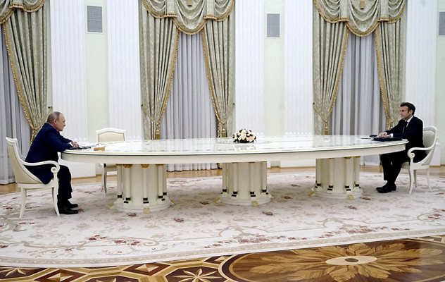 Френският президент Еманюел Макрон и руският му колега Владимир Путин седят в Кремъл на срещуположните страни на огромна овална бяла маса, на разстояние от 6 м един от друг.