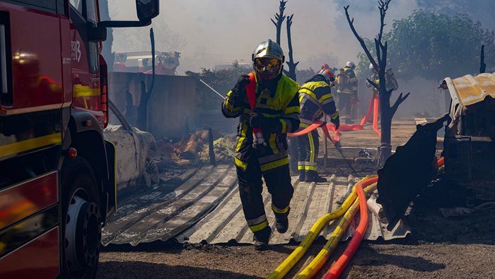 Пожарникари гасят къща, запалила се от горския пожар в Арл, Южна Франция.