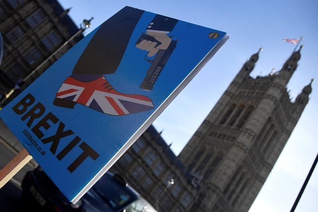 Демонстрант държи плакат по време на протест срещу Брекзит пред сградата на парламента в Лондон.  СНИМКИ: РОЙТЕРС