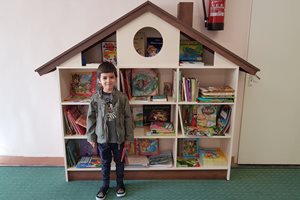 До библиотеката в детската градина към Италианския лицей. Къщичката е проектирана и направена собственоръчно от майка му и баща му.