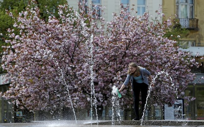 Жена пълни бутилка с вода от фонтан в Прага