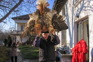 77-годишният Методи Десов показва една от сурвакарските маски, които той е изработил от дърво и пера от кокошки и пуйки.
СНИМКА: ГЕОРГИ КЮРПАНОВ