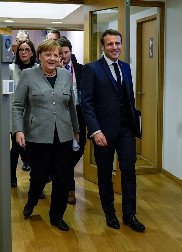 Ангела Меркел и Еманюел Макрон излизат развеселени от двустранна среща във втория ден от преговорите за бюджета на ЕС. 