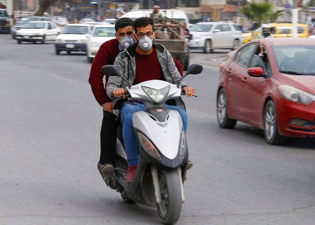Мъже в Ирак управляват мотор с маски.
