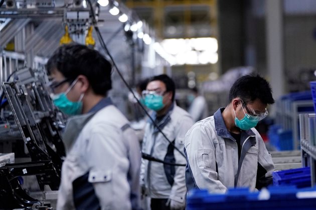 Работници с маски във фабрика в Шанхай