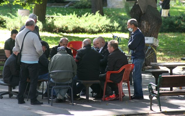 Група мъже играят карти в Цар-Симеоновата градинка, малко от тях са с маски.
