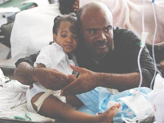 Мъж утешава 7-годишния Десле Улачине в полева болница.