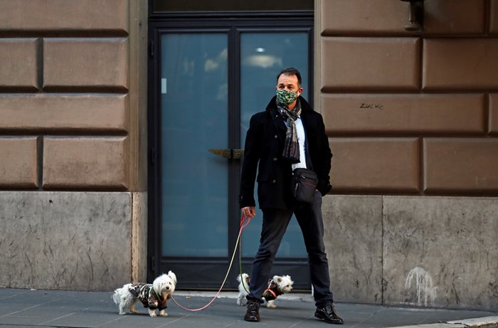Мъж разхожда кучетта си в Рим, докато италианските власти затягат мерките за празниците. 